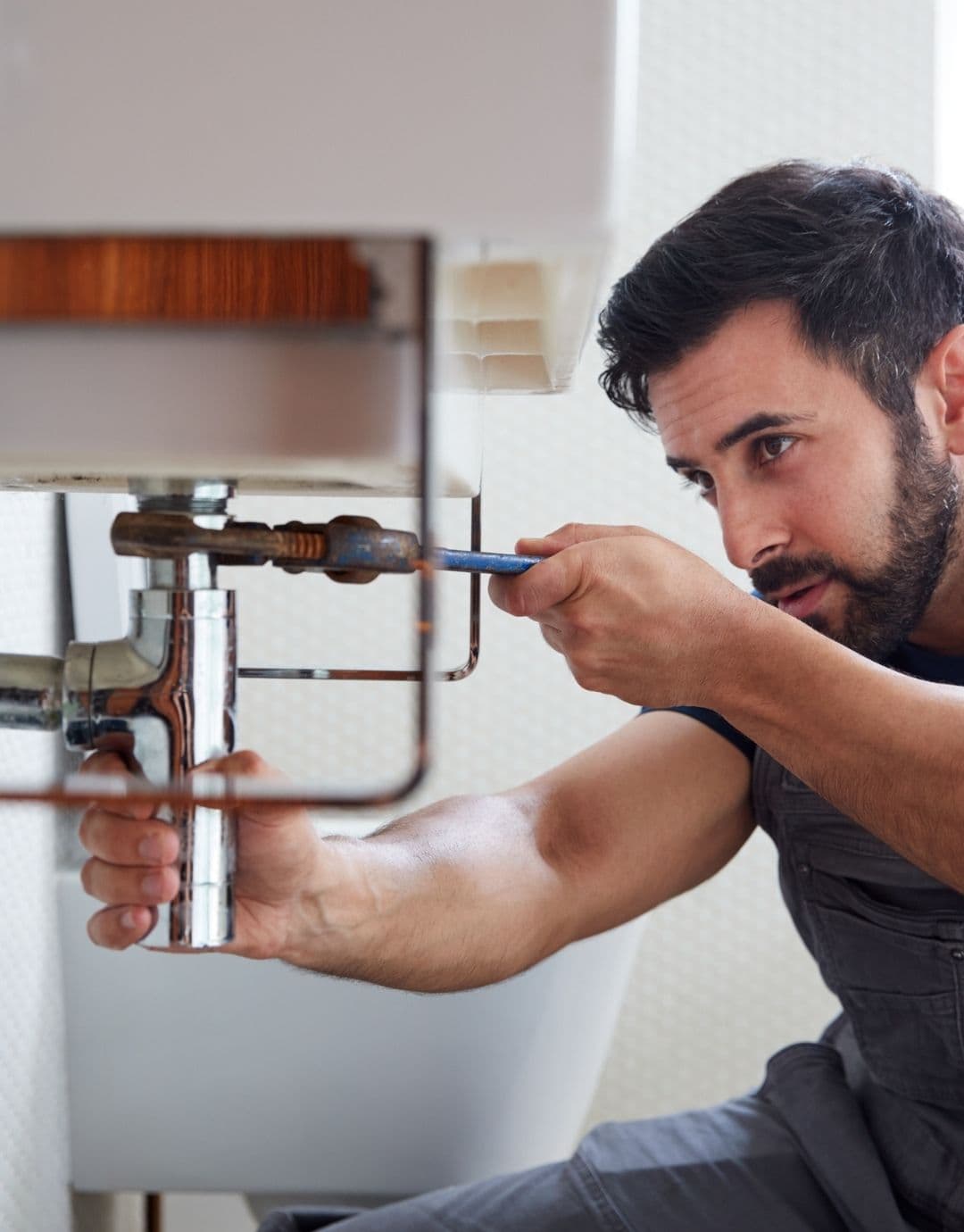 Plombier intervenant sous un lavabo pour démonter un siphon